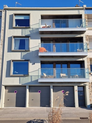 A multi-story residential building with balconies, large windows, and a garage.