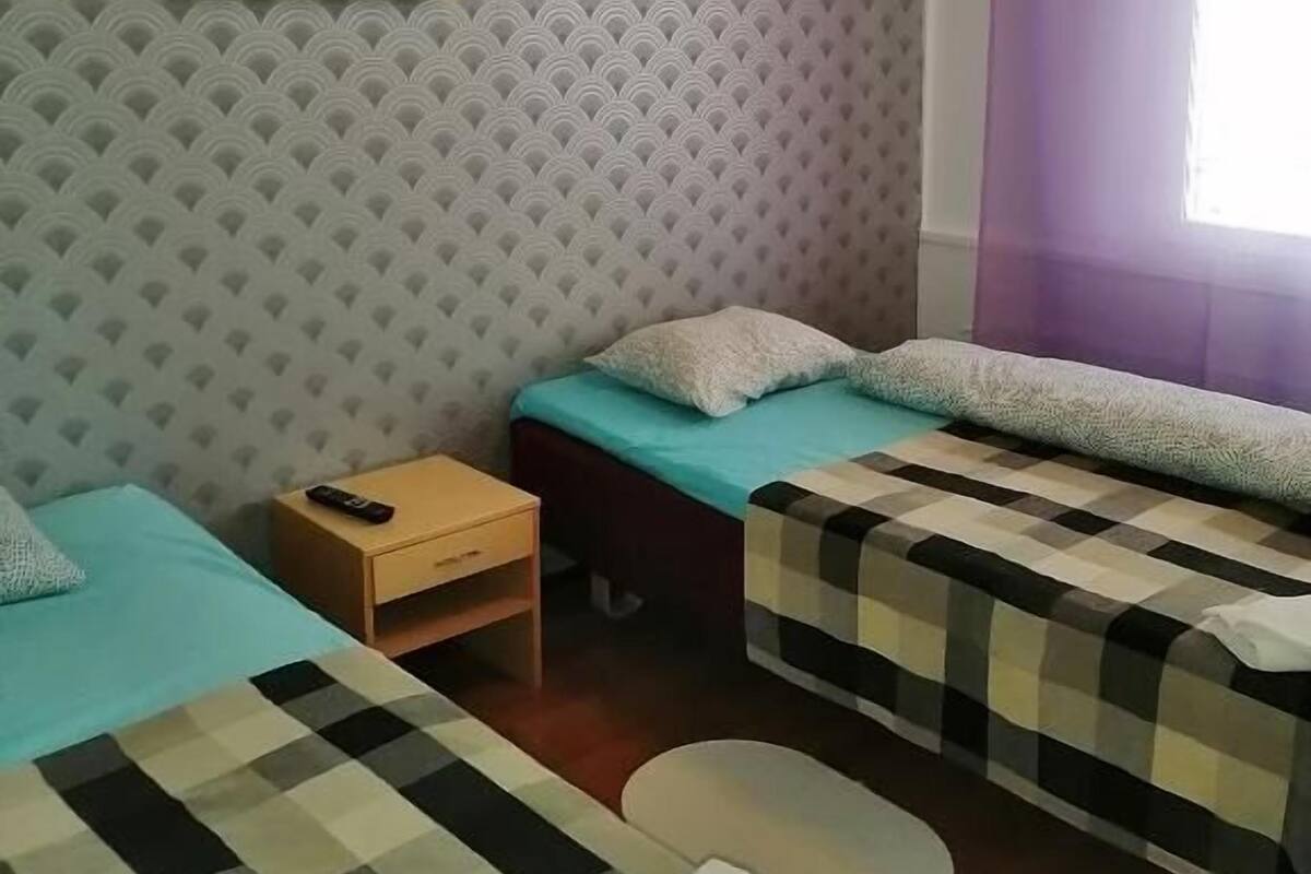 A room with two beds, a small table, and a painting on the wall.