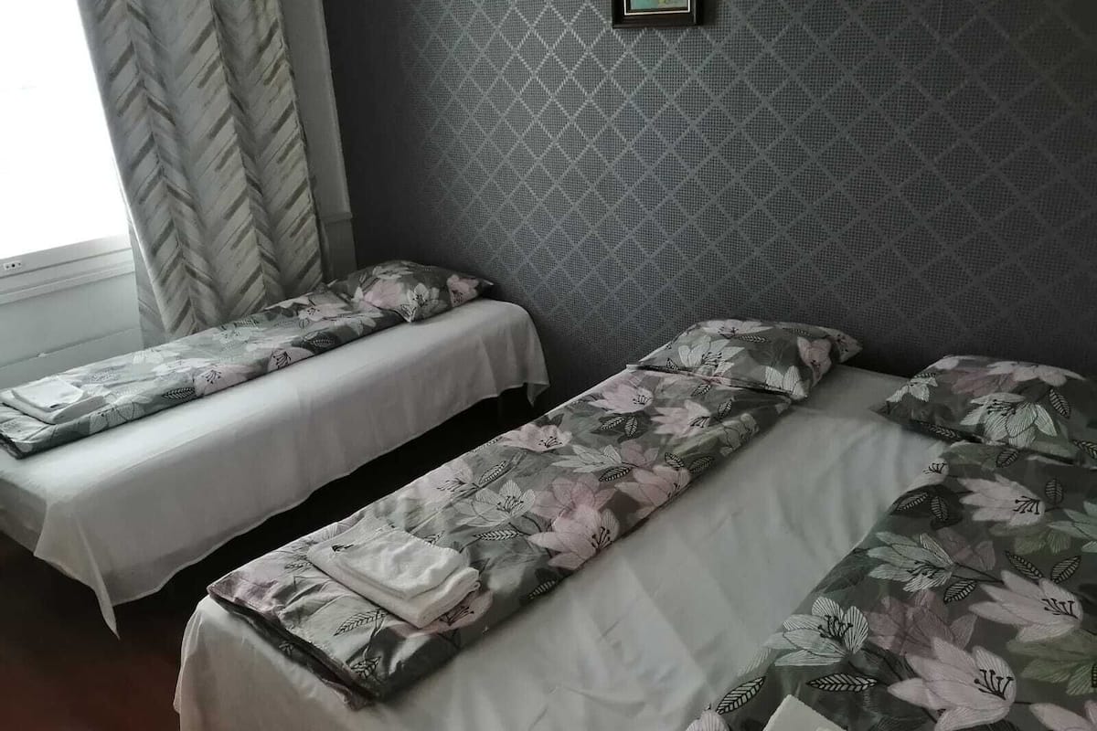 A room with two single beds, each with floral-patterned bedding and pillows.
