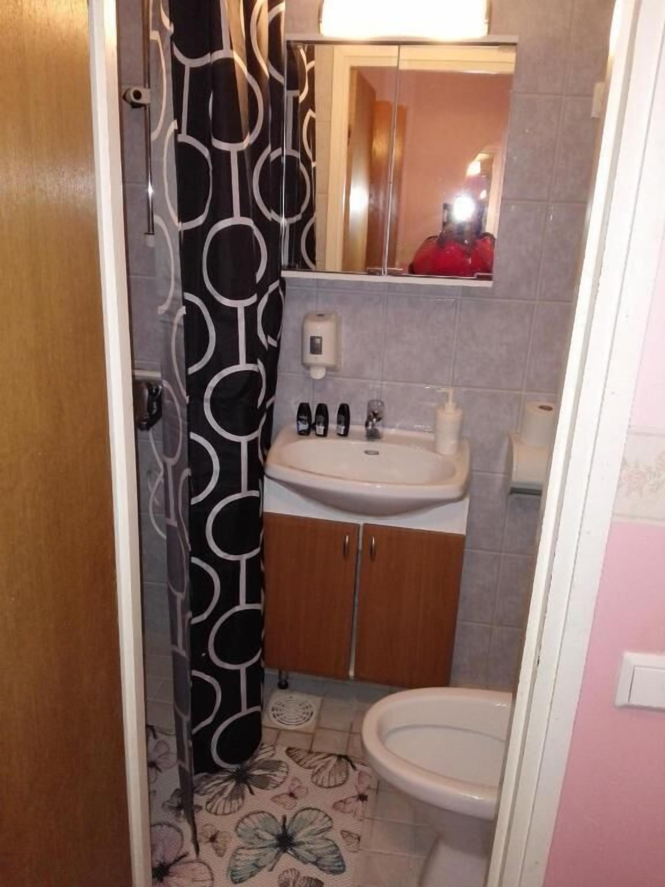 A bathroom with a toilet, sink, and shower curtain.