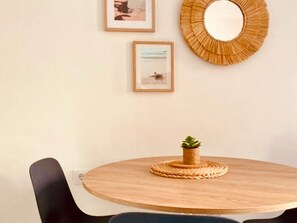 Une table ronde en bois, sur laquelle repose un set de table en fibres tressées et une petite plante en pot.