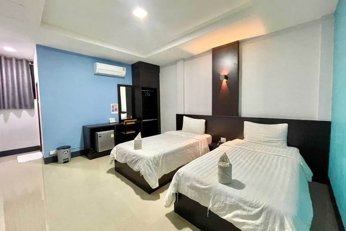 Une chambre d’hôtel avec deux lits, un bureau, un miroir et un appareil de climatisation.