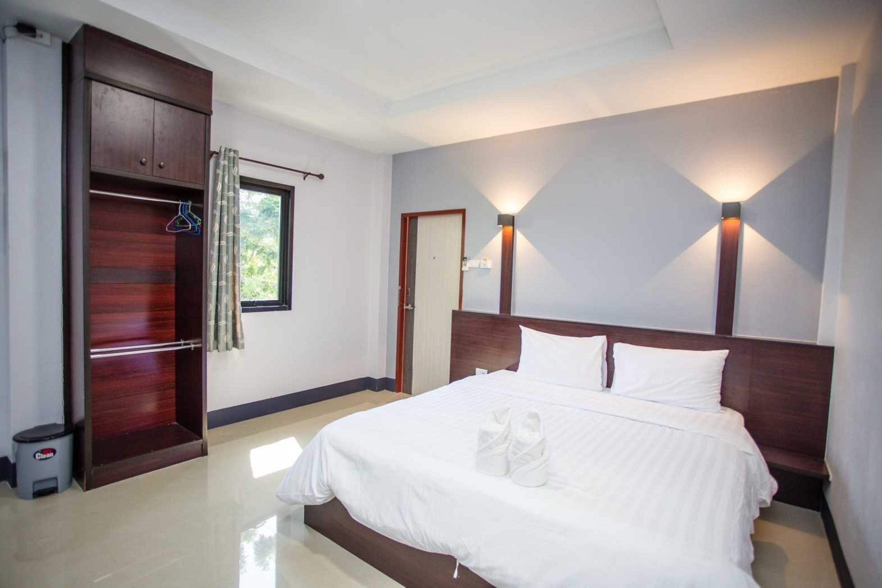A hotel room with a large bed, a wardrobe, and two wall-mounted lights.
