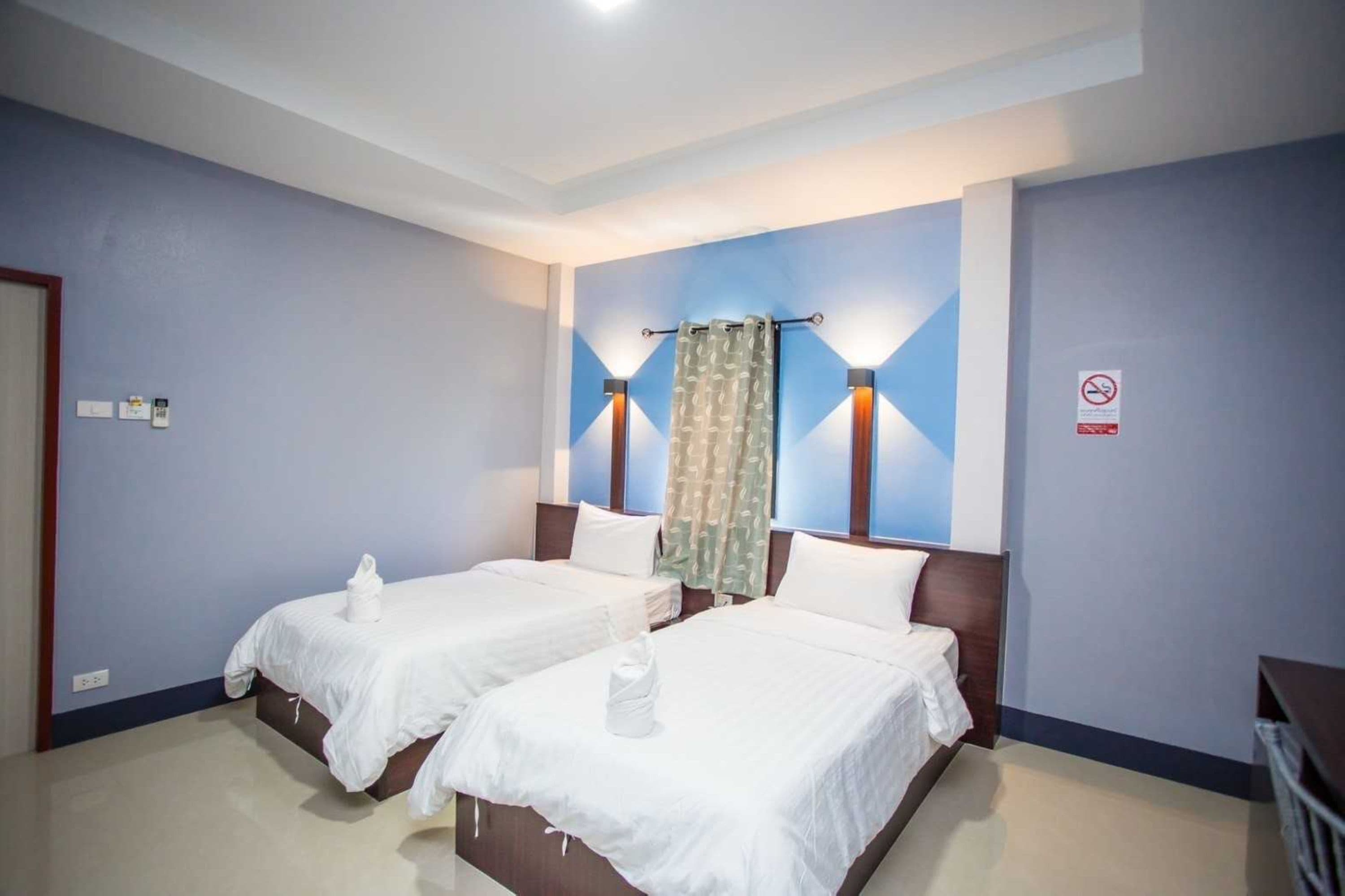 Habitación de hotel con dos camas, zona de ducha y un escritorio pequeño.