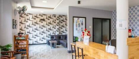 A modern reception area with a wooden counter, seating, and a patterned wall.