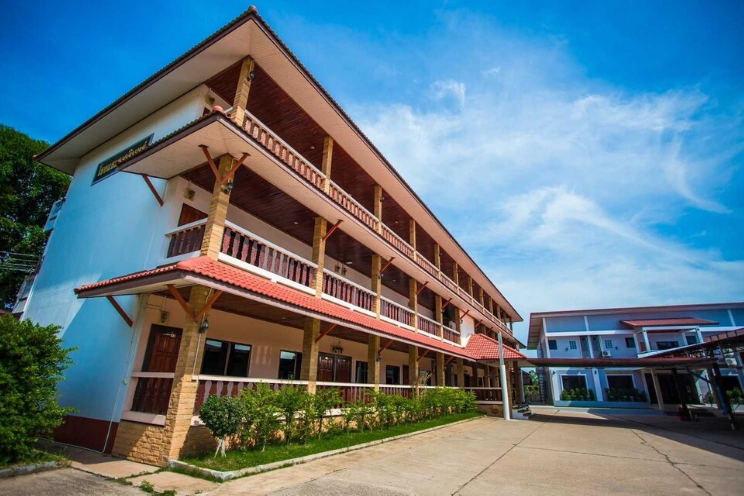A multi-story building with a balcony on the second floor, a covered entrance, and a clear sky.