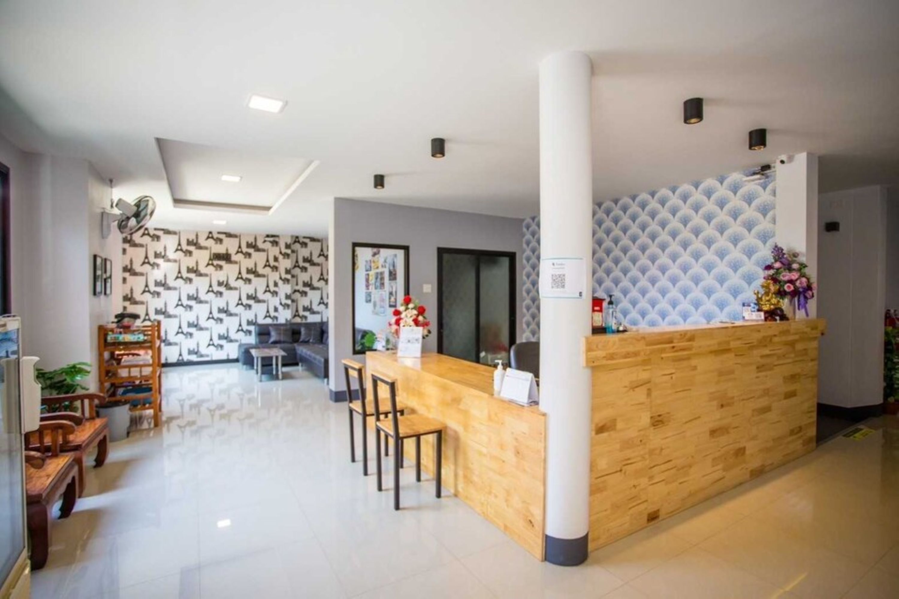 Una hall d'albergo moderna con una scrivania in legno, area salotto e parete decorata.