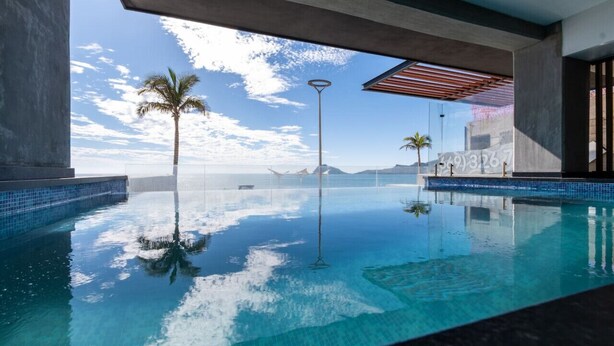 Ein Pool mit unendlicher Optik, blauem Wasser, Palmen und Blick auf den Ozean und die Berge.