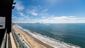 Blick auf die Küste mit Strand, Meer und einer entfernten Skyline.