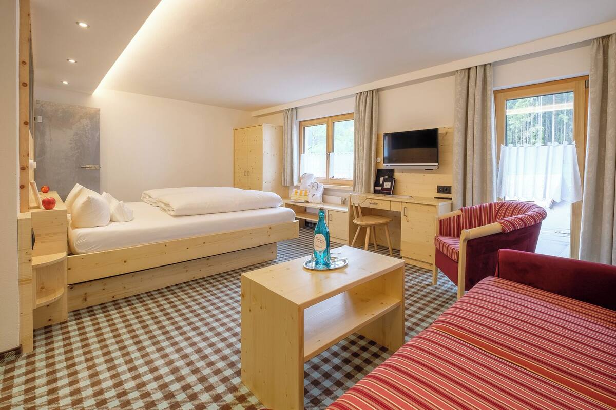 A hotel room with a bed, a desk, a TV, and a window with curtains.