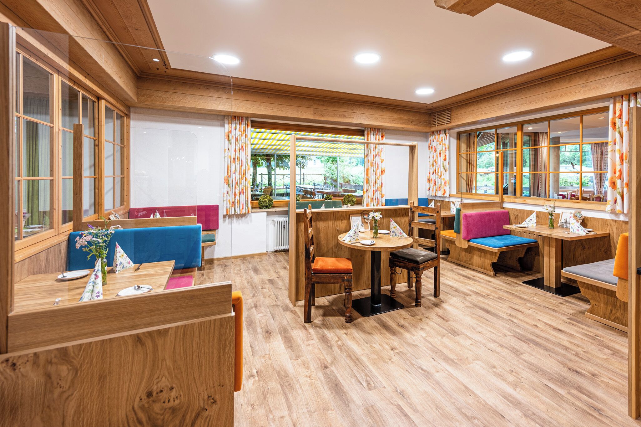 A cozy, wooden-floored room with seating areas, large windows, and a view of the outdoors.