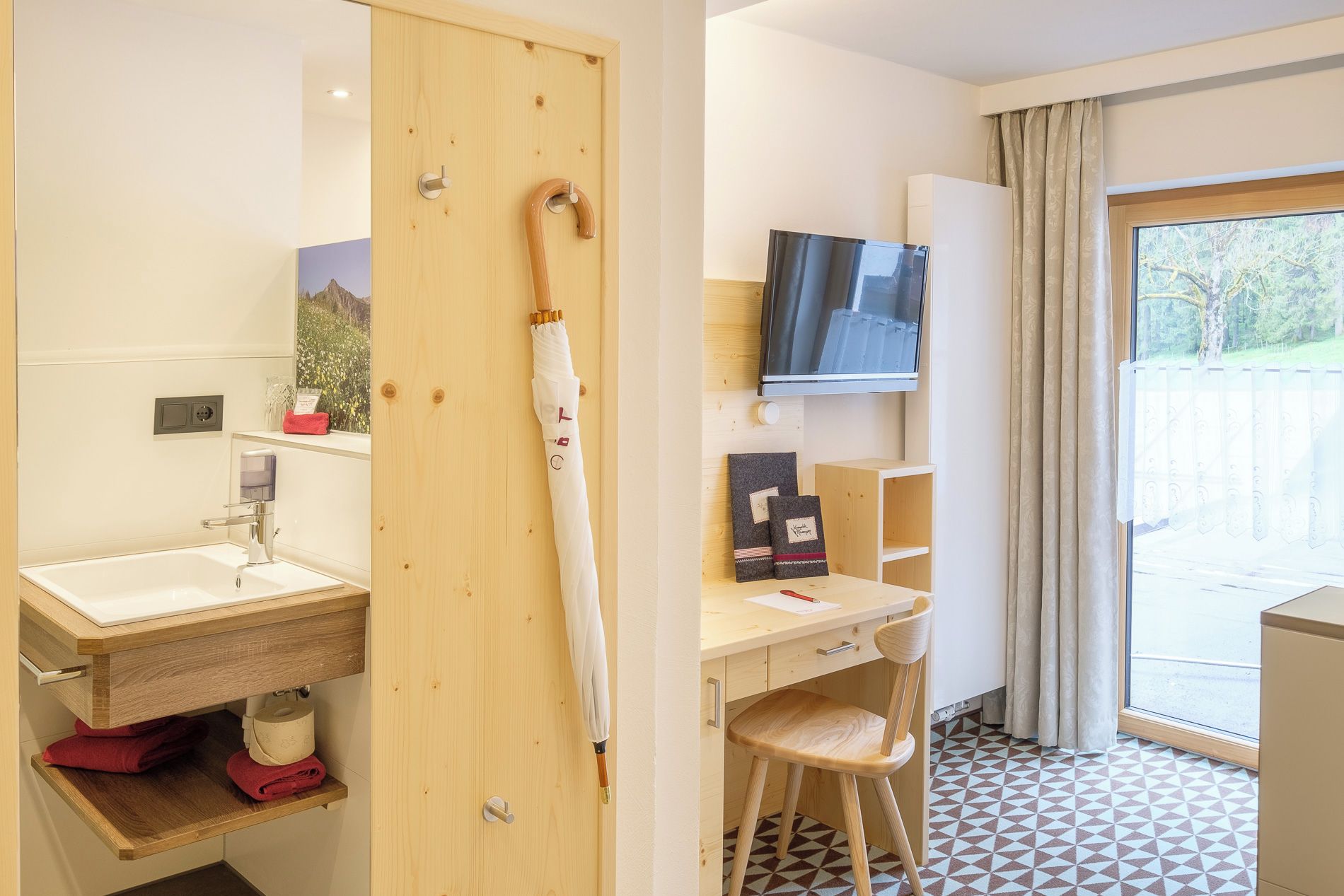A bathroom with a sink, towel rack, and a wooden door.