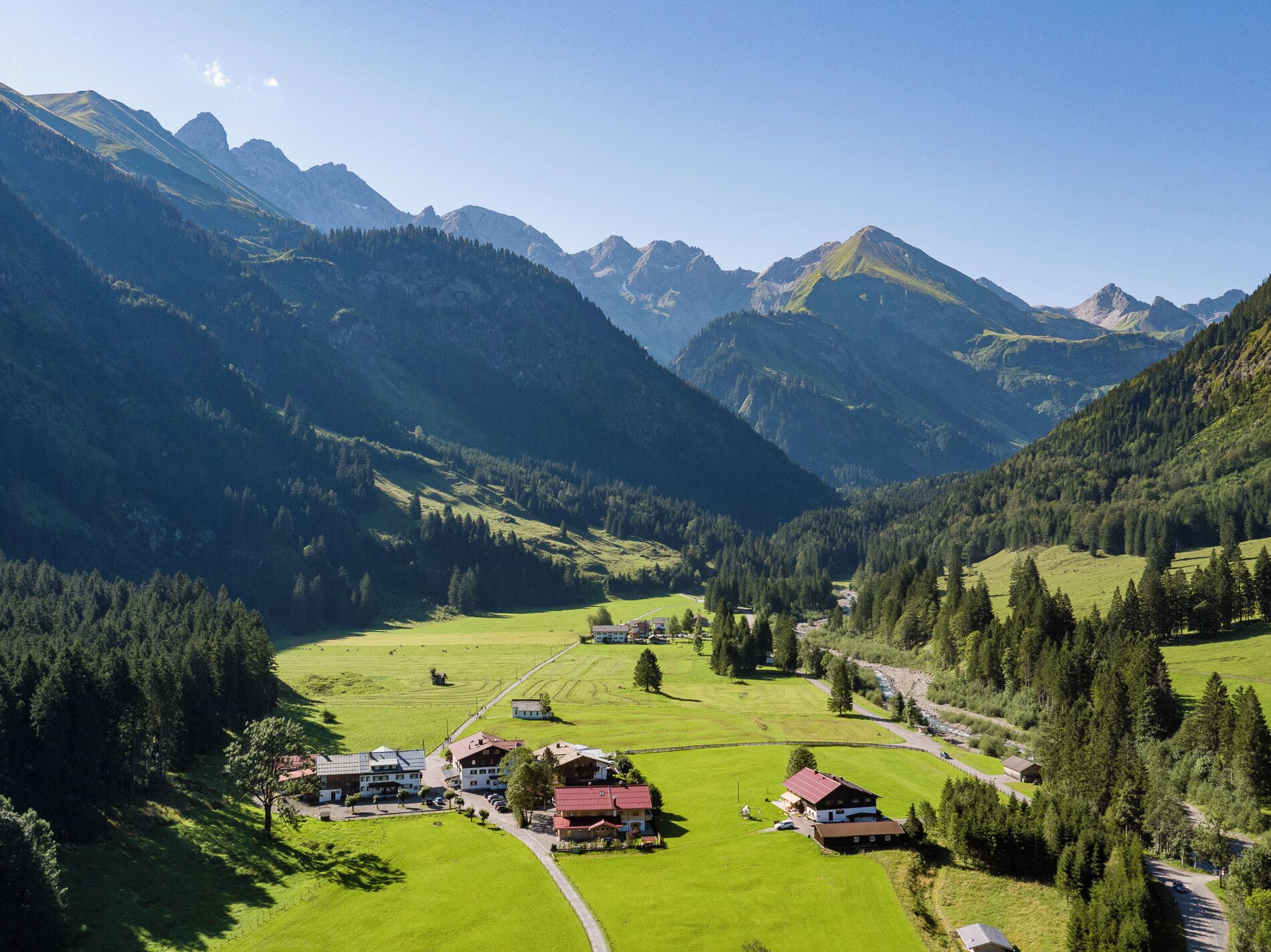 Un paisaje montañoso con un valle, casas y una carretera.