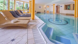 Una amplia piscina cubierta con sillones de descanso y un diseño decorativo de azulejos.
