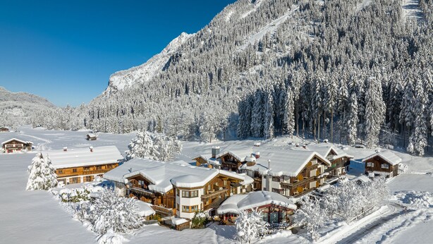 Una cabaña nevada con varias cabañas de madera, rodeada de un bosque y una montaña.