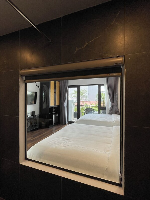A modern hotel room with a large bed, a TV, and a view of the outdoors.