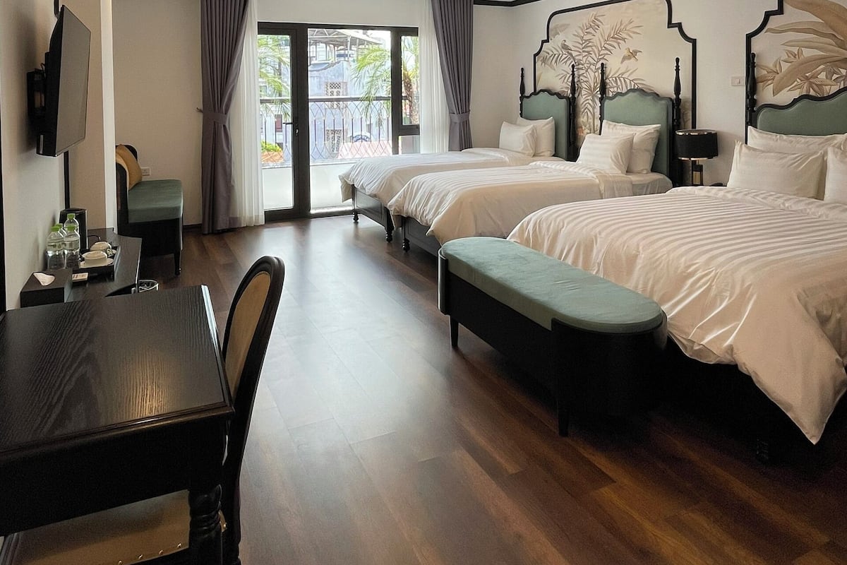 A hotel room with two beds, a dining table, and a TV.
