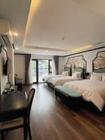 A hotel room with two beds, a dining table, and a TV.