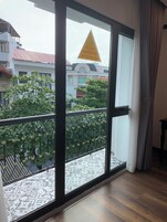 Una habitación con un amplio ventanal corredizo que da a un balcón con baldosas estampadas.