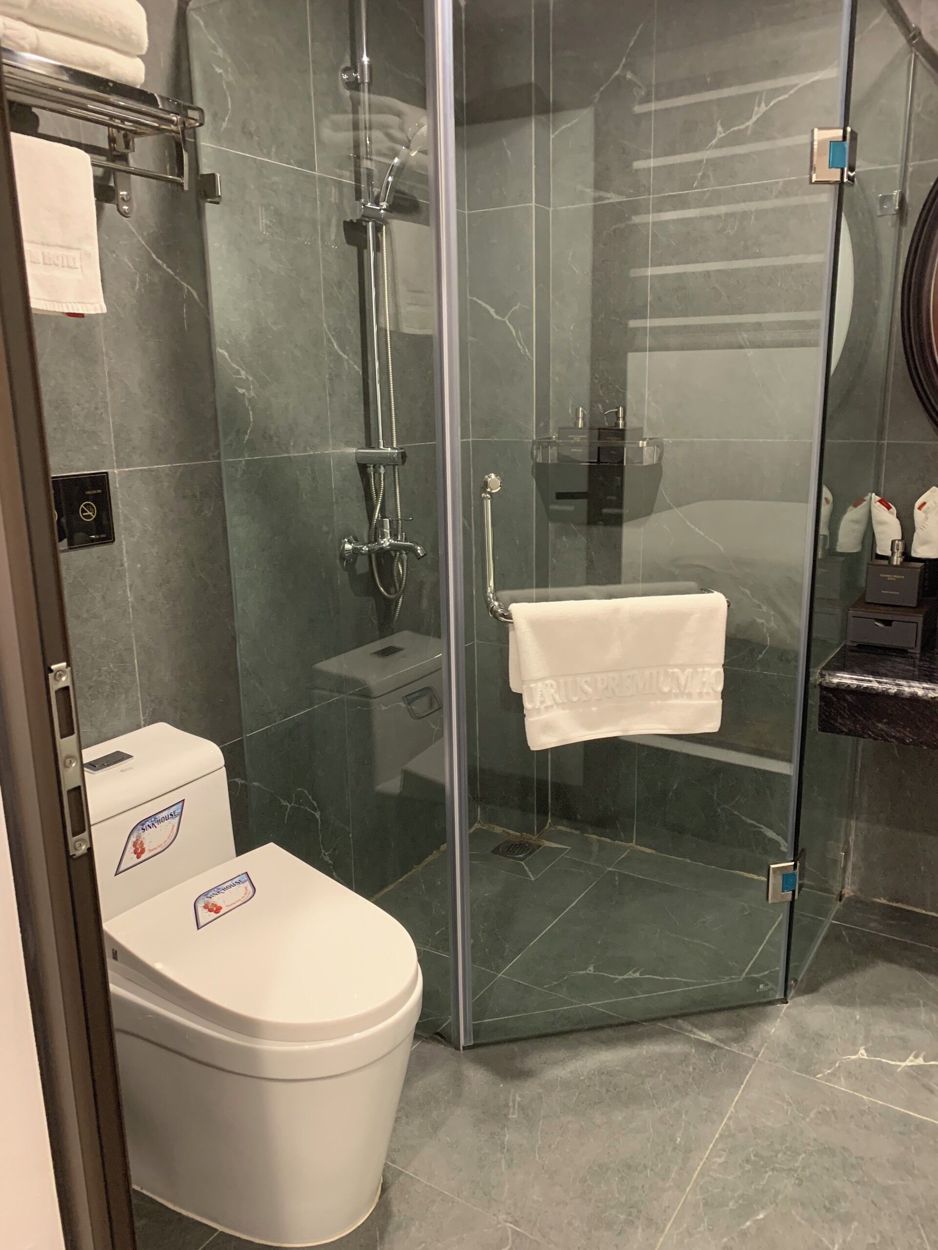 A modern bathroom with a glass-enclosed shower, a white toilet, and a glass door.