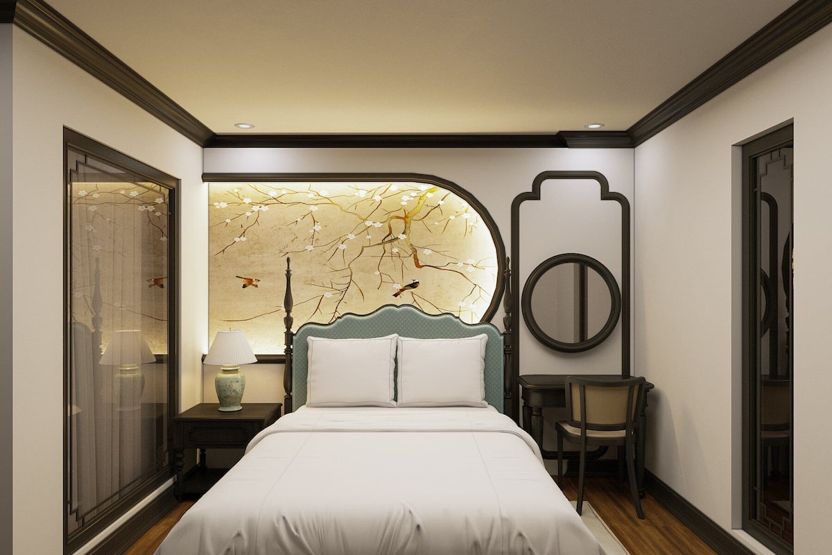 A bedroom with a large bed, a nightstand, a chair, and a decorative wall piece.