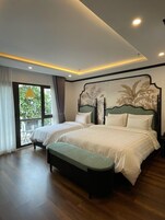 A bedroom with two beds, a bench, and a balcony with curtains.
