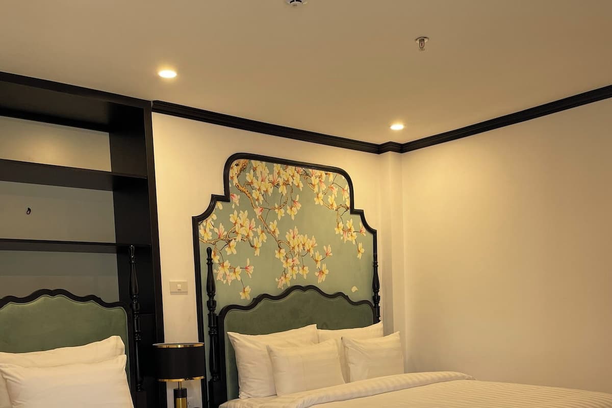 A hotel room with two beds, a decorative headboard, and a wooden floor.