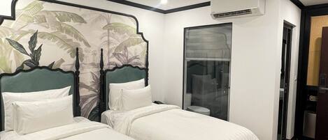 A hotel room with two beds, a large window, and an air conditioning unit.