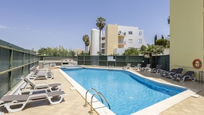 A swimming pool with sun loungers and a metal ladder. - City & Sea view apartment, Meia Praia Lagos (Lagos)