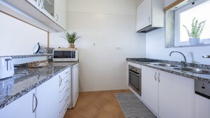 A compact kitchen with white cabinets, a microwave, a toaster, and a sink. - City & Sea view apartment, Meia Praia Lagos (Lagos)