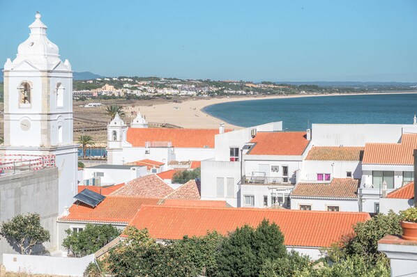 A coastal town with white buildings, red roofs, and a prominent white church tower.
