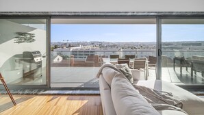 Een moderne woonkamer met een grote schuifglazen deur die uitkomt op een dak terras.