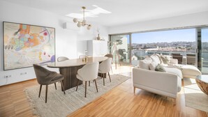 Een moderne woonkamer met een eethoek, grote ramen en uitzicht op de stad.