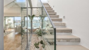 Een modern interieur met een glazen trap die leidt naar een balkon met uitzicht over de stad.