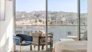 Een balkon met uitzicht op een stadsgezicht, een blauwe stoel, een bank en een bed.