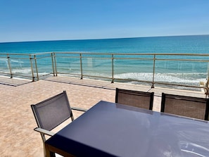 Relax in this oceanfront seating area with a table and chairs, offering a clear view of the sea.