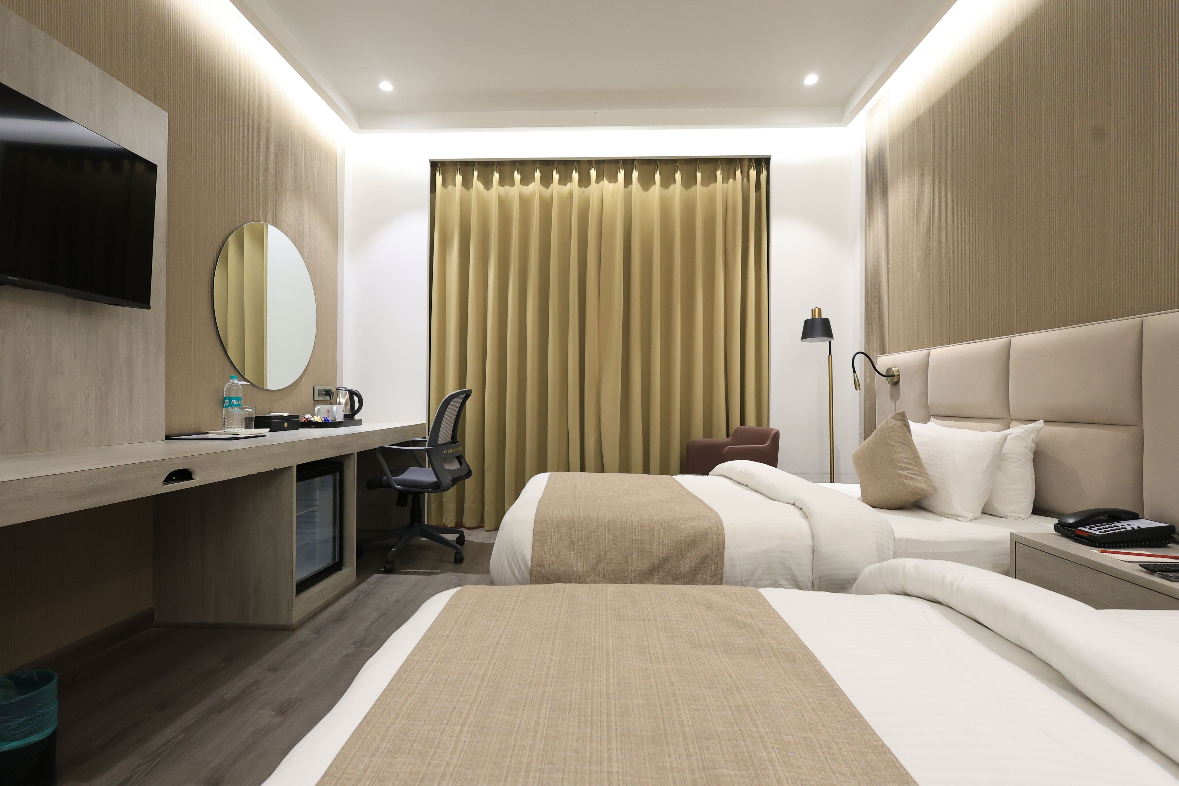Ein Hotelzimmer mit Bett, Schreibtisch, Stuhl, Fernseher und einem fensterbepflanzten Fenster.