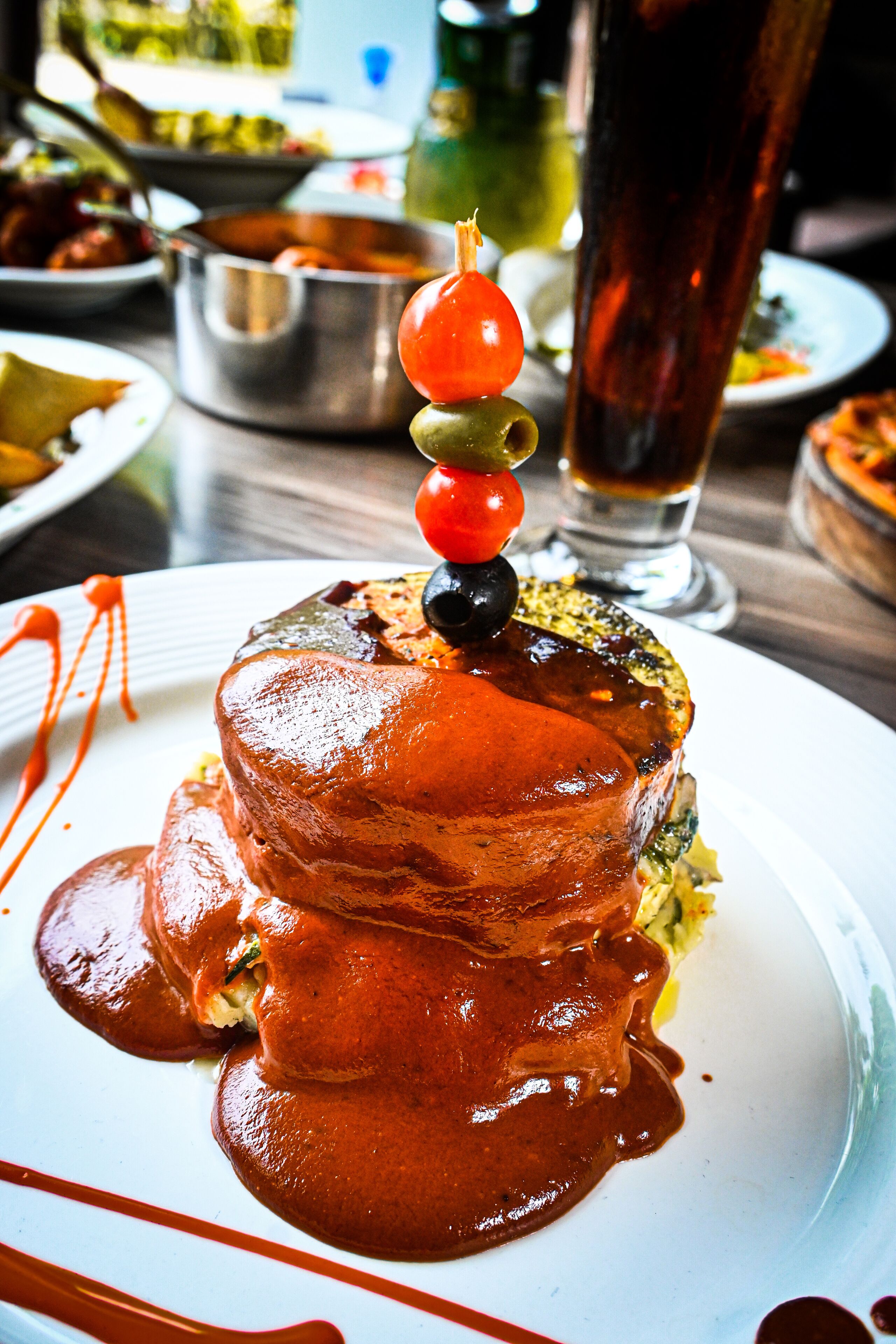 Een dessert met een kersje erop, omringd door saus, op een wit bord.