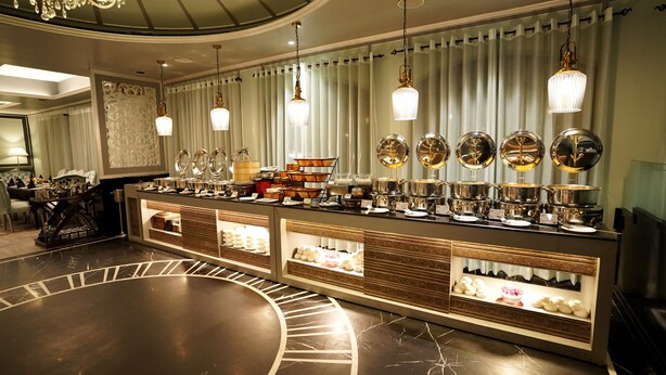 A hotel lobby with a buffet area featuring a variety of food items and a decorative fountain. - Hotel Swarn Towers (Bareilly)