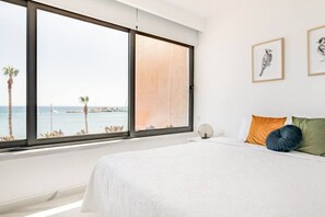 Enjoy a serene sea view from the large window, featuring a comfortable bed and minimalist decor.