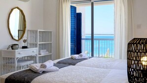 Habitación de hotel con cama, escritorio, espejo y vista al mar.