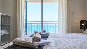 Una habitación de hotel con cama, toallas, una silla y vista al mar.