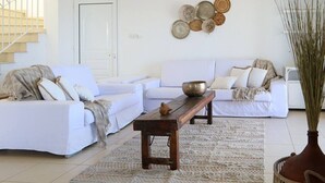 Una sala de estar con un sofá, una mesa de centro de madera, un tapiz tejido y platos decorativos en la pared.
