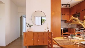 Una mesa de comedor de madera con sillas, un espejo en la pared y una cocina al fondo.