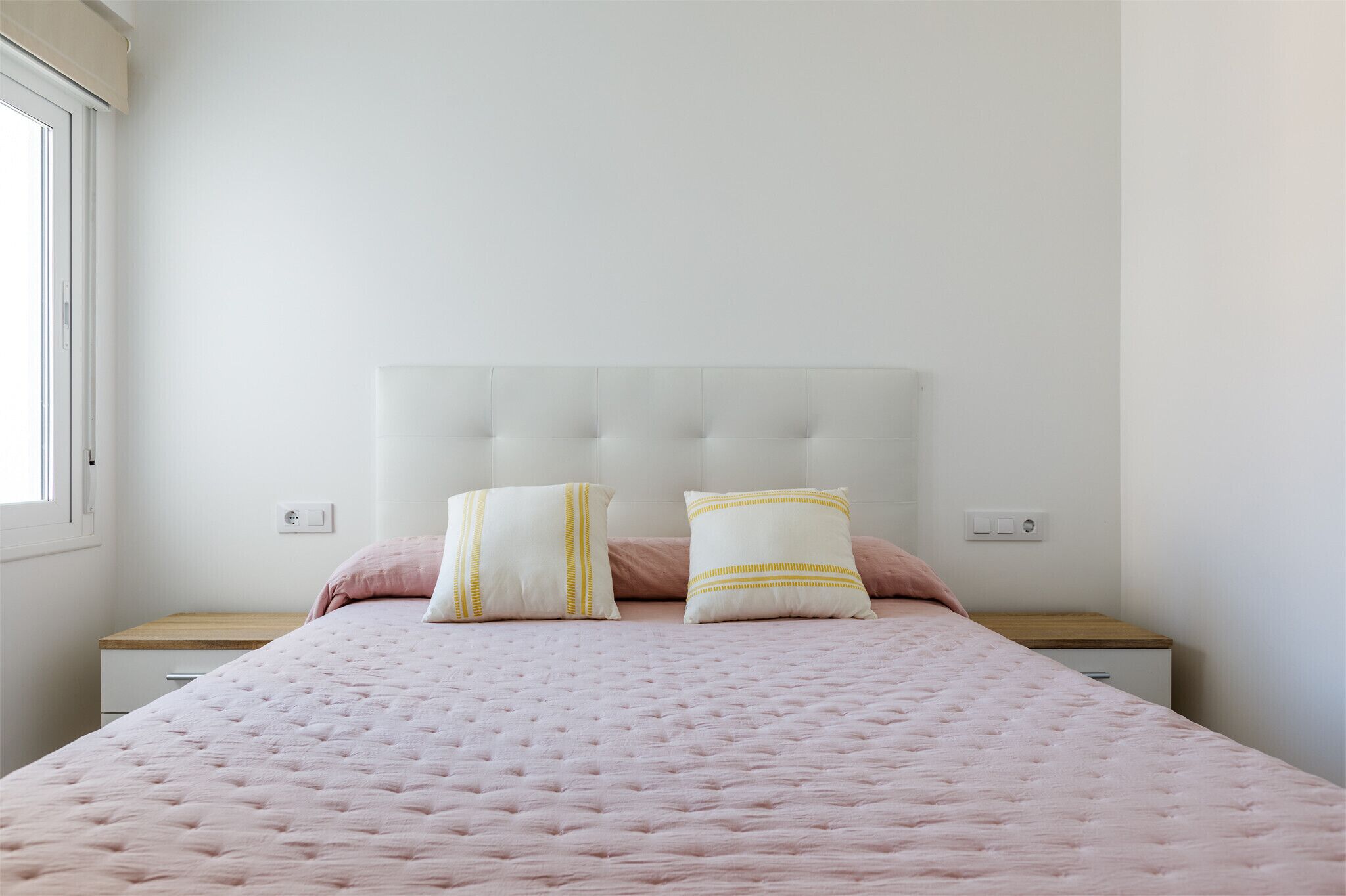 Ein Schlafzimmer mit einem Bett, zwei Nachttischen und einem Fenster.