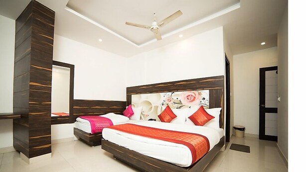 A modern hotel room with a large bed, a desk, and a ceiling fan. - Hotel Sunrise Dx @ Opposite New Delhi Railway Station (New Delhi)