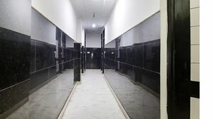 A corridor with black and white tiled walls and a marble floor, leading to an elevator. - Hotel Sunrise Dx @ Opposite New Delhi Railway Station (New Delhi)