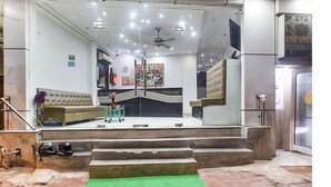 A hotel lobby with a reception desk, a sofa, a staircase, and a ceiling fan. - Hotel Sunrise Dx @ Opposite New Delhi Railway Station (New Delhi)