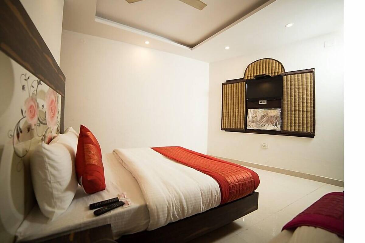 Une chambre d’hôtel moderne équipée d’un lit, d’oreillers, d’une couverture, d’une télécommande et d’un téléviseur fixé au mur.
