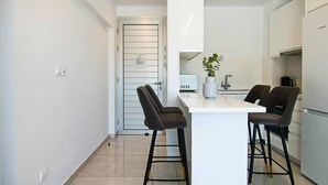 A modern kitchen with a central island, bar stools, and a potted plant. - Phaedrus Living Seaside Executive Flat Harbour 207 (Paphos)